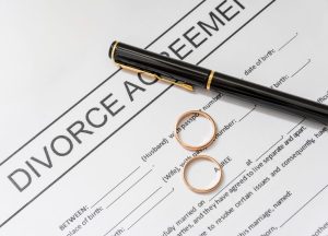 Document officiel intitulé Divorce Agreement avec un stylo plume et deux alliances posées sur le papier